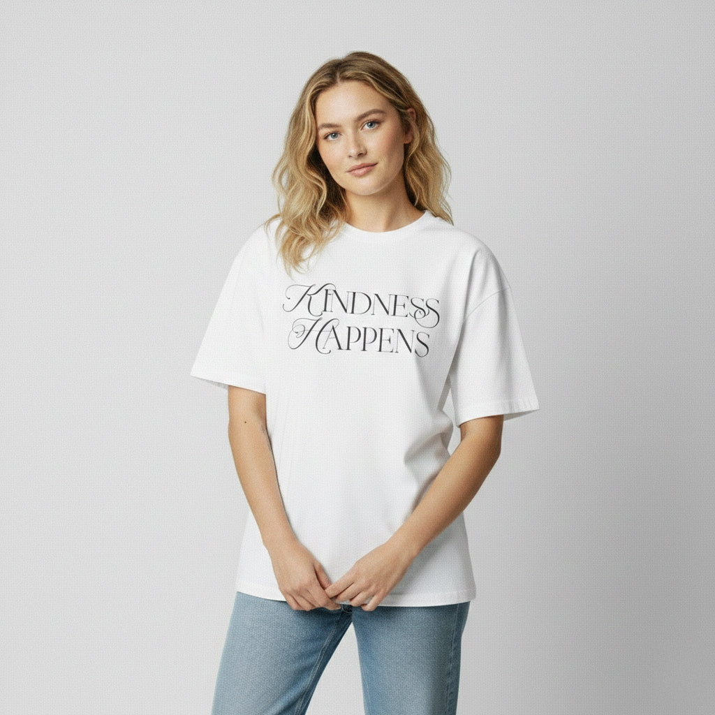 Professional studio shot of a model wearing the 7722 premium white unisex cotton tee featuring a sophisticated black "Kindness Happens" script graphic.