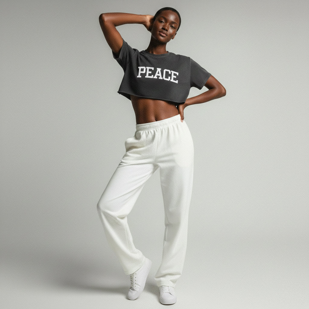 Professional studio photography of a model wearing the 7722 snow-washed black Peace crop top with a bold white minimalist graphic and raw edge hem.