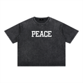 Unisex boxy-fit 100% cotton tee in a dark mineral wash with a centered white "PEACE" block-letter graphic.