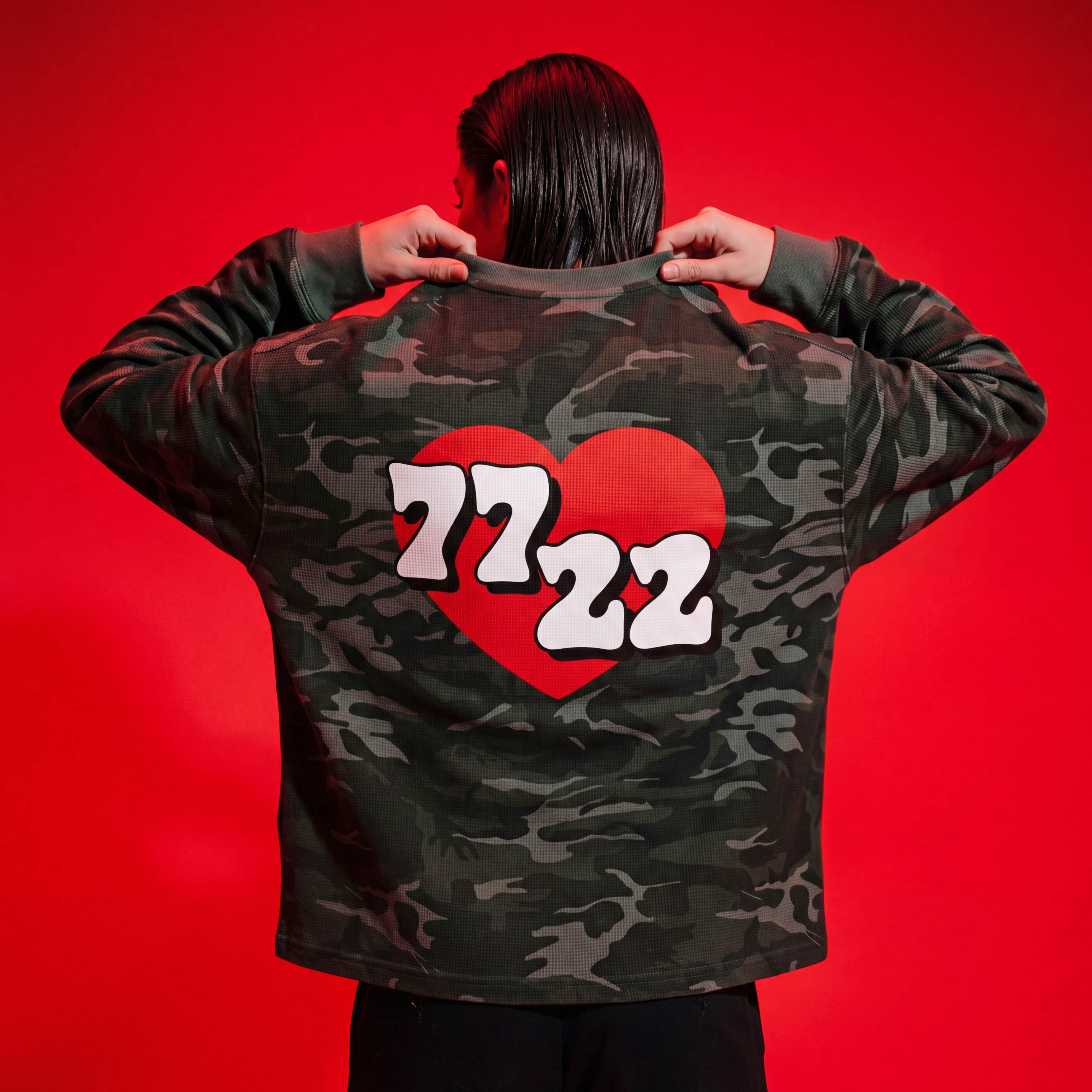Person wearing a camouflage jacket with a red heart and numbers on the back against a red background