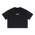 A black short-sleeve crewneck t-shirt with the word 'PEACE' printed in white block letters across the chest, displayed flat against a solid white background.